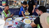 Pemandangan serupa terlihat di sebuah restoran di Baghdad. Seorang anak laki-laki lain melayani pelanggan, menyajikan makanan dengan wajah serius, seolah ia sudah terbiasa dengan rutinitas tersebut. REUTERS/Ahmed Saad