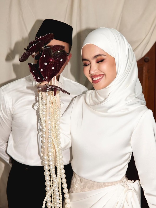 Memakai hijab putih polos dililit rapi dengan gaya basic wrap, Fira atau Sashfir berpose tersenyum bahagia. Gaya hijab Sashfir ini timeless dan praktis, cocok untuk hari pernikahan. Foto: Dok. Instagram @sashfir.