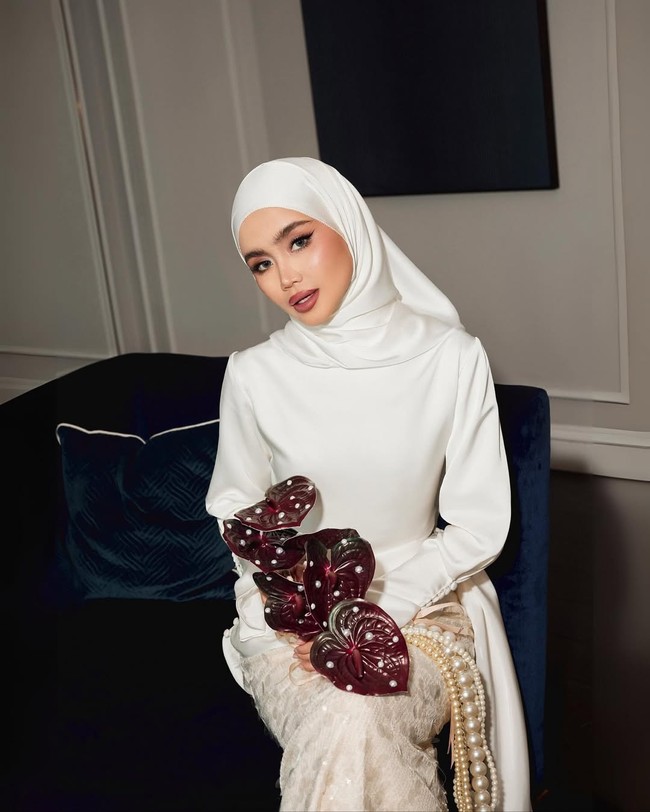 Hijab putih satin polos dipadukan Sashfir dengan gaya clean tucked, tanpa lipatan berlebihan. Kesan anggun semakin kuat karena kain hijab tampak berkilau di bawah cahaya. Foto: Dok. Instagram @sashfir.