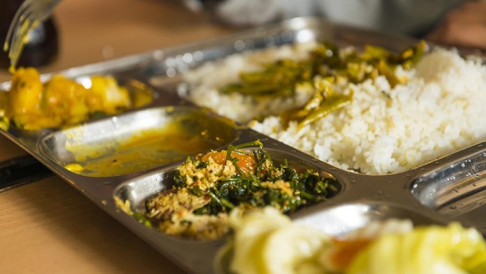 Course, different kinds of Sri Lanka dishes on the restaurant table, rice, vegetable, jack fruit, flat bread, water, soya sauce ready to eat.