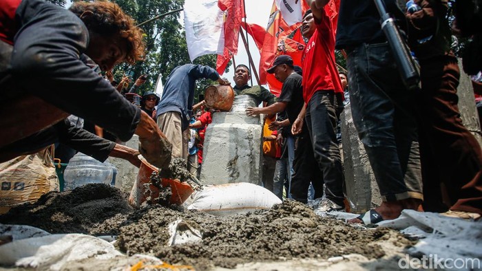 Seorang massa aksi dicor dengan semen di Jalan Medan Merdeka Selatan saat memperingati Hari Tani Nasional, Rabu (24/9/2025). Aksi ini dilakukan sebagai bentuk protes dramatik terhadap kondisi agraria negara.