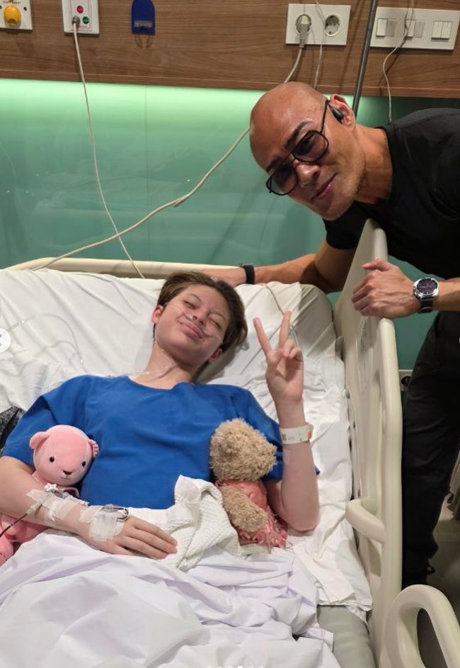 Saat pemulihan pasca operasi, Nada juga didampingi oleh ayah angkatnya, Deddy Corbuzier. Terlihat Nada yang masih lemas terbaring di ranjang rumah sakit sambil memeluk 2 boneka kesayangannya. Foto: Instagram/@nada_tarina_putri