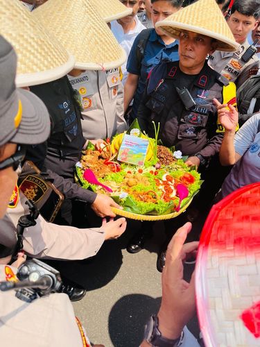Polisi memberikan tumpeng kepada petani di peringatan Hari Tani Nasional di Monas, Jakarta Pusat, Rabu (24/9/2025).