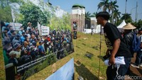 Seorang massa aksi melihat pameran foto wajah petani di depan DPR/MPR, Jakarta, Rabu (24/9/2025). 