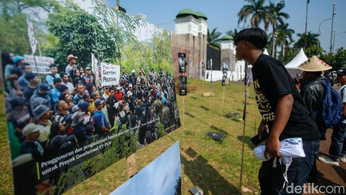 Seorang massa aksi melihat pameran foto wajah petani di depan DPR/MPR, Jakarta, Rabu (24/9/2025).