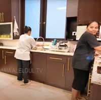 Dapur terlihat modern dengan kabinet berwarna cokelat tua dan pegangan emas yang elegan. Peralatan dapur seperti microwave, kulkas, dan mesin kopi juga lengkap tersedia. Foto: YouTube/MAIA ALELDUL TV