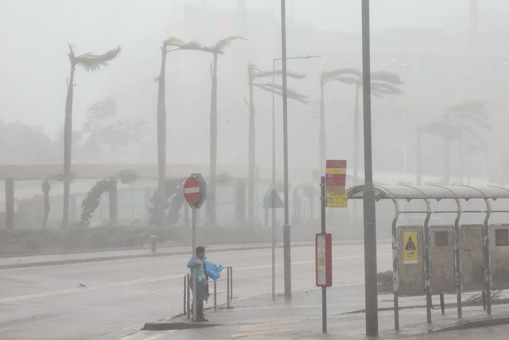 Seorang wanita berpegangan pada rambu lalu lintas untuk menjaga keseimbangan melawan angin kencang dari Topan Super Ragasa di Hong Kong, Cina, 24 September 2025. (REUTERS/Tyrone Siu)