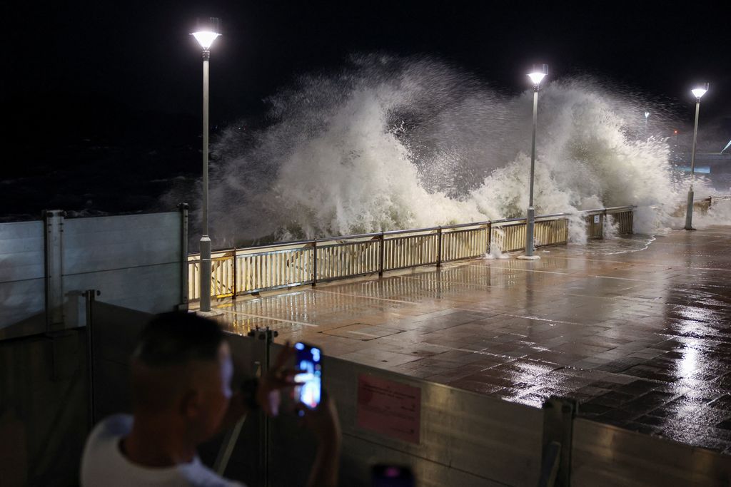 Seorang warga mengambil foto ombak besar dari pantai sebelum Topan Super Ragasa berada pada titik terdekatnya di Hong Kong, Cina, 23 September 2025. (REUTERS/Tyrone Siu)