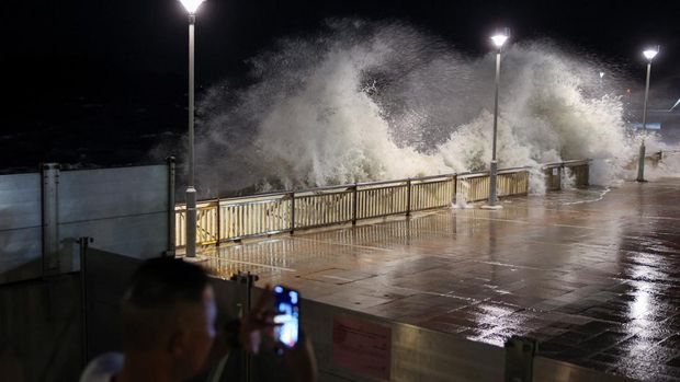 Seorang warga mengambil foto ombak besar dari pantai sebelum Topan Super Ragasa berada pada titik terdekatnya di Hong Kong, Cina, 23 September 2025. (REUTERS/Tyrone Siu)