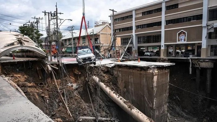 A vehicle is removed from the edge of a hole in the ground after a road collapsed near a hospital in Bangkok on September 24, 2025. A portion of a busy road in the Thai capital caved in early on September 24, leaving a massive 50-metre-deep hole in front of a main hospital and forcing people nearby to evacuate. (AFP)