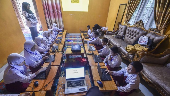 Guru mengawasi pelaksanaan Asesmen Nasional Berbasis Komputer (Gelombang kedua) pelajar kelas V SDN 51 Simpang Kubu Kandang di rumah salah seorang warga di Batang Hari, Jambi, Kamis (25/9/2025). Asesmen yang berlangsung selama dua hari dan diikuti sebanyak 27 siswa tersebut terpaksa dilaksanakan di rumah salah satu guru yang berjarak dua kilometer lebih dari sekolah, disebabkan buruknya jaringan internet di sekolah. ANTARA FOTO/Wahdi Septiawan/rwa.