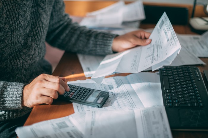 Close-up of male hands with a utility bill, a lot of checks and a calculator on the table. The man considers the costs of gas, electricity, heating. The concept of increasing tariffs for services
