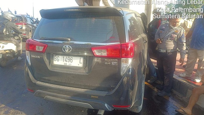 Polisi saat mengevakuasi Innova hitam yang tabrak tiang LRT di Palembang, usai kabur tabrak pejalan kaki.
