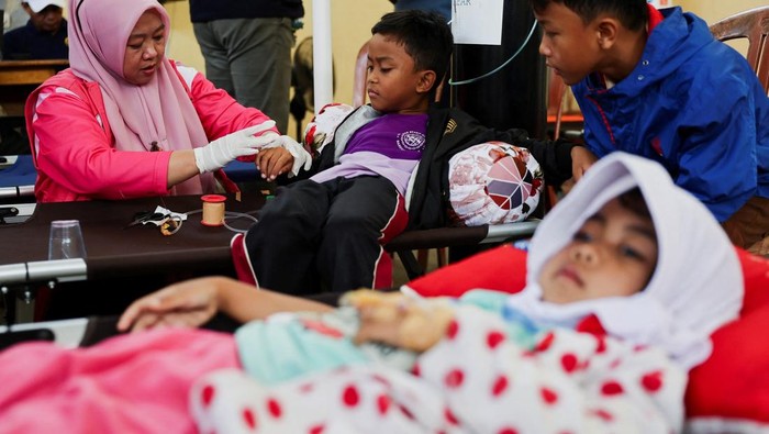 Naya Raisa Nuraini, 14, lies on a velbed while receiving treatments for food poisoning after eating government-sponsored free school meals, at a makeshift clinic inside a districts hall in Bandung, West Java province, Indonesia, September 25, 2025. REUTERS/Willy Kurniawan