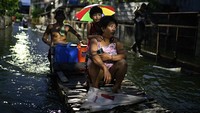 Sejumlah anak-anak dan orang dewasa terlihat menggunakan rakit sederhana dari bambu maupun perahu kecil untuk menyeberangi jalan yang terendam. REUTERS/Noel Celis