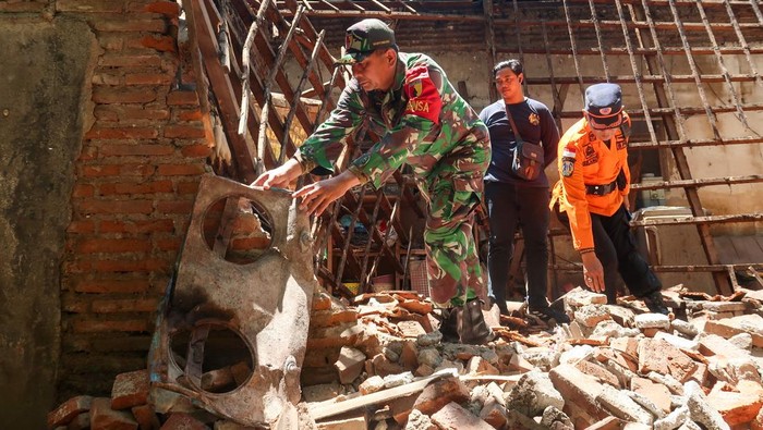 Anggota TNI memindahkan puing bangunan yang ambruk akibat gempa di Desa Bajulmati, Wongsorejo, Banyuwangi, Jawa Timur, Jumat (26/9/2025). Gempa 5,7 magnitudo yang terjadi di timur laut Banyuwangi pada Kamis (25/9) sore itu mengakibatkan tujuh bangunan di Banyuwangi rusak ringan hingga berat. ANTARA FOTO/Budi Candra Setya/bar