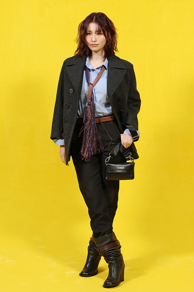 Di tahun ketiganya menjadi brand ambassador Onitsuka Tiger, Momo TWICE menghadiri Milan Fashion Week dengan office look. Terdiri dari paduan blazer hitam, kemeja biru, dasi beraksen rumbai, serta scrunched black boots. Foto: Getty Images