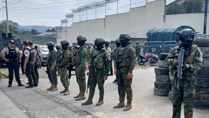 Police and military officers stand guard in front of a prison in Esmeraldas, Ecuador on September 25, 2025. Clashes between rival gangs claimed at least 10 lives in the second deadly riot in an Ecuadoran prison in days, police said Thursday. (Photo by Antony QUINTERO / AFP)