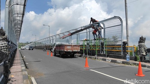 Proses pemasangan atap pada pagar pengaman sepanjang Jembatan Tukad Bangkung, Badung, pada Kamis (25/9/2025). (Foto: Agus Eka/detikBali)