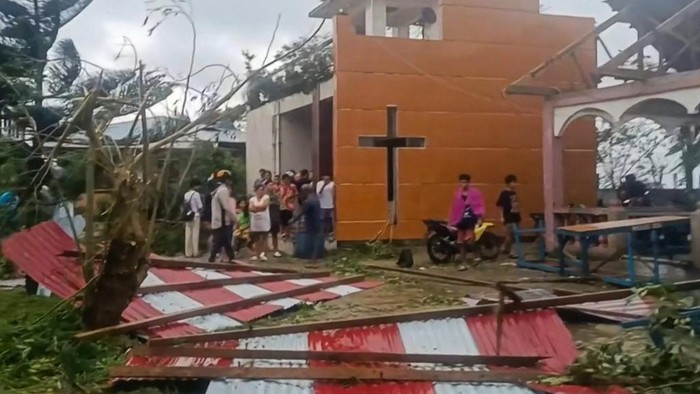 This screen grab taken from UGC video footage courtesy of Facebook user Jerome Martinez taken and received on September 26, 2025 shows people looking at the damage caused by Severe Tropical Storm Bualoi to the Parish of the Immaculate Concepcion Church in Batuan town, Masbate province. The Philippines evacuated hundreds of thousands of people and confirmed at least three deaths on September 26 as the severe tropical storm battered a country still feeling the effects of Super Typhoon Ragasa. (Photo by Handout / various sources / AFP) / RESTRICTED TO EDITORIAL USE - MANDATORY CREDIT 