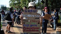 Peserta aksi mengangkat poster bertuliskan “Guru ≠ Beban Negara” sebagai kritik terhadap kondisi guru honorer yang masih jauh dari kesejahteraan. 