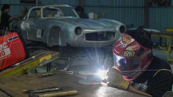 Pekerja melakukan proses produksi replika mobil klasik di Tuksedo Studio, Gianyar, Bali, Sabtu (27/9/2025). Tuksedo Studio yang memproduksi sejumlah tipe replika mobil klasik buatan tangan dengan harga berkisar Rp2 miliar hingga Rp5 miliar per unit tersebut terus mengembangkan produk-produk kreasinya sebagai salah satu upaya untuk mendukung peningkatan sektor industri dan ekonomi kreatif di Indonesia. ANTARA FOTO/Fikri Yusuf/sgd