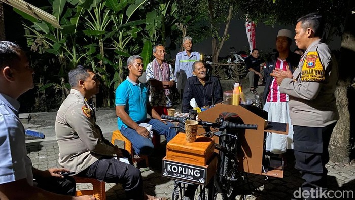 Aipda Abdul Mukid Murtadho berkeliling kampung menggunakan sepeda angin sambil membawa kopi gratis untuk warga
