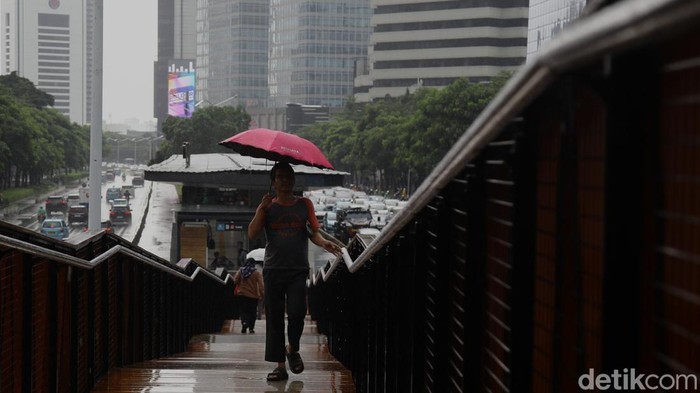 Warga menembus gerimis di JPO Pinisi Jl Jendral Sudirman, Jakarta, Senin (29/9/2025).