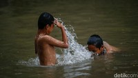 Anak-anak mencoba berbagai gaya renang saat berenang di sungai Kalimalang, meski arus cukup deras.