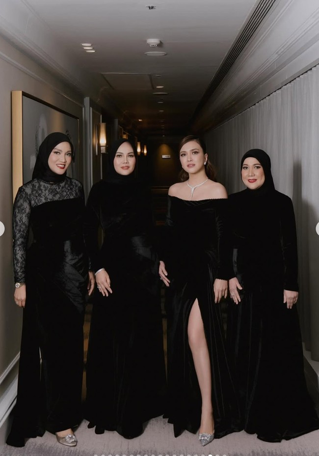 Shandy mengenakan gaun panjang berbahan velvet berwarna hitam yang elegan. Model off-shoulder menonjolkan bahu dan tulang selangka, memberikan kesan anggun sekaligus seksi. Bagian bawah gaun memiliki belahan tinggi di sisi depan yang menambah kesan glamor dan mempertegas siluet tubuh. Foto: Instagram/@shandyaulia