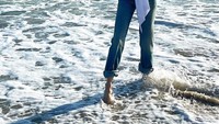 Senyumnya Nicole menikmati desiran ombak pantai yang menerjang kakinya.