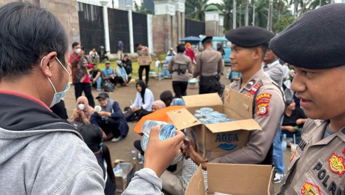 Polisi membagikan air mineral dan roti kepada massa di depan DPR, Selasa (30/9/3035).