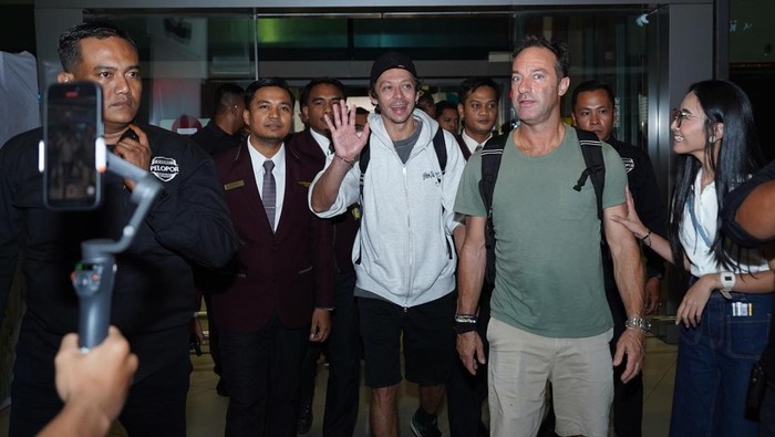 Legenda MotoGP Valentino Rossi melambaikan tangan saat tiba di Bandara Soekarno-Hatta, disambut antusias ribuan fans pada Senin malam (29/9/2025).