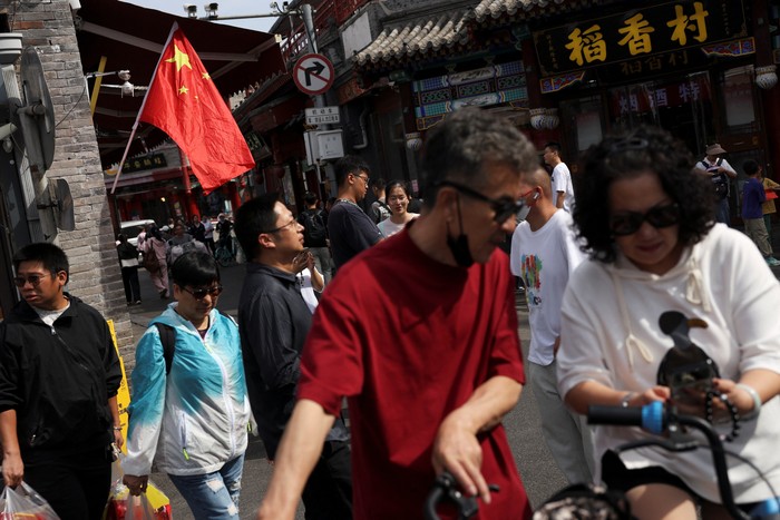 Visitors walk past a Chinese flag decorating a shop in the Shichahai area on National Day, the first day of Chinas eight-day Golden Week holiday, in Beijing, China October 1, 2025. REUTERS/Florence Lo