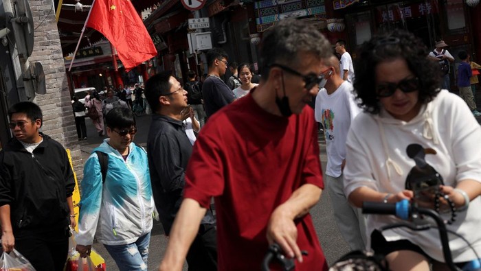 Visitors walk past a Chinese flag decorating a shop in the Shichahai area on National Day, the first day of China's eight-day Golden Week holiday, in Beijing, China October 1, 2025. REUTERS/Florence Lo