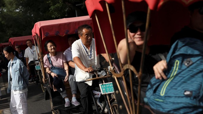Visitors walk past a Chinese flag decorating a shop in the Shichahai area on National Day, the first day of Chinas eight-day Golden Week holiday, in Beijing, China October 1, 2025. REUTERS/Florence Lo