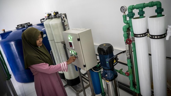Anggota Kelompok Penyediaan Air Minum dan Sanitasi (KPSPAMS) Banjarsari Bergerak, Nur Khalimah membawa galon untuk diisi air minum di tempat desalinasi air minum Dukuh Brangsong, Desa Banjarsari, Sayung, Kabupaten Demak, Jawa Tengah, Rabu (1/10/2025). Pemprov Jawa Tengah bekerja sama dengan Universitas Diponegoro (Undip) Semarang mengembangkan teknologi desalinasi untuk mengolah air payau menjadi air tawar layak minum untuk memenuhi kebutuhan air bersih masyarakat. ANTARA FOTO/Aprillio Akbar/nym.