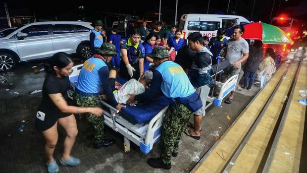 Polisi membantu warga yang terluka saat mereka dibawa ke rumah sakit di Kota Bogo, provinsi Cebu, Filipina tengah, pada tanggal 1 Oktober 2025, setelah gempa bumi berkekuatan 6,9 skala Richter mengguncang Filipina tengah, meruntuhkan bangunan dan menewaskan sedikitnya 19 orang. (Photo by Alan Tangcawan / AFP)