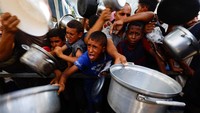 Warga Palestina membawa panci kosong saat mengantre makanan di dapur umum Nuseirat, Gaza, Minggu (28/9/2025). REUTERS/Mahmoud Issa