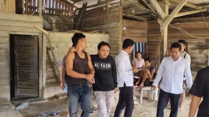 Tersangka (baju cokelat) saat diamankan polisi di tempat kerjanya.