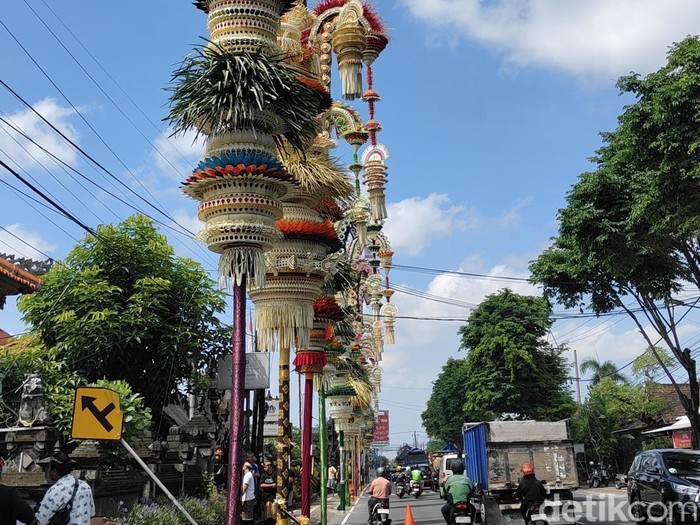 Belasan penjor dengan beragam ornamen berdiri megah di sepanjang jalan depan Pura Desa Adat Kapal, Kecamatan Mengwi, Badung, Kamis pagi (2/10/2025). (Agus Eka/detikBali)