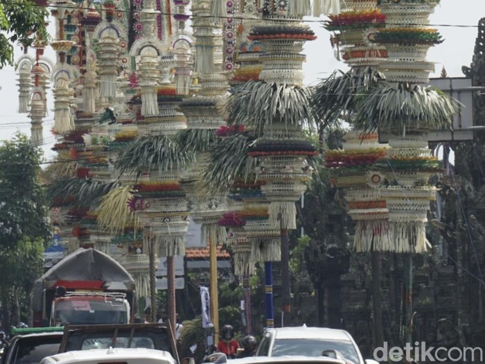 Belasan penjor dengan beragam ornamen berdiri megah di sepanjang jalan depan Pura Desa Adat Kapal, Kecamatan Mengwi, Badung, Kamis pagi (2/10/2025). (Agus Eka/detikBali)