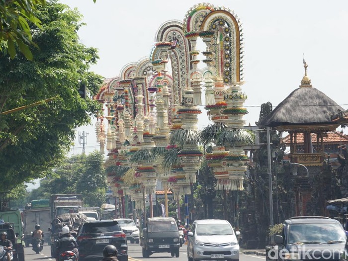 Belasan penjor dengan beragam ornamen berdiri megah di sepanjang jalan depan Pura Desa Adat Kapal, Kecamatan Mengwi, Badung, Kamis pagi (2/10/2025). (Agus Eka/detikBali)