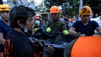 Tim penyelamat mengevakuasi jenazah korban gempa. Selagi operasi penyelamatan terus berlanjut, para korban selamat di kota Bogo yang paling parah terkena dampak menghadapi pemadaman listrik yang meluas, rumah-rumah yang hancur, dan fasilitas medis yang kewalahan. Foto: REUTERS/Eloisa Lopez