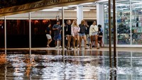 Para wisatawan berjalan melewati jalanan yang terendam banjir setelah Badai Gabrielle menghantam Ibiza. REUTERS/Francisco Ubilla
