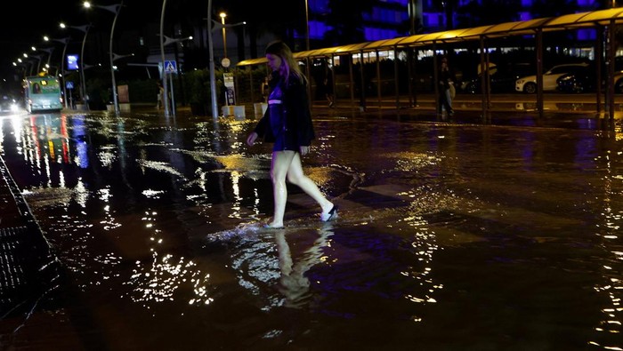 Tourists walks past a flooded street after storm Gabrielle hit the island in Ibiza, Spain September 30, 2025. REUTERS/Francisco Ubilla