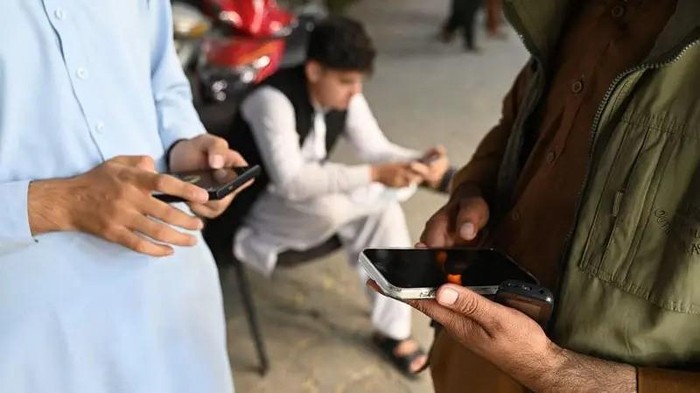 Para pria Afghanistan menggunakan ponsel mereka di Kabul, 1 Oktober 2025. Jaringan seluler dan internet dipulihkan di seluruh Afghanistan pada 1 Oktober, setelah otoritas Taliban sempat memutus layanan telekomunikasi. (WAKIL KOHSAR/AFP)