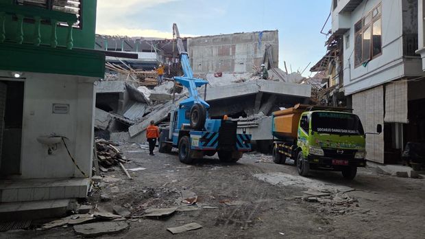 Petugas melakukan asesmen untuk menemukan tanda kehidupan di balik reruntuhan sebelum mengerahkan alat berat crane.