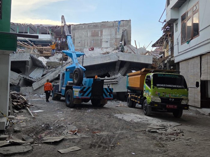 Petugas melakukan asesmen untuk menemukan tanda kehidupan di balik reruntuhan sebelum mengerahkan alat berat crane.