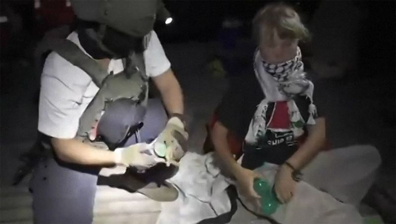 This video grab taken from a handout footage released by the Israeli Foreign Ministry on October 1, 2025  shows an Israeli soldier with Swedish climate activist Greta Thunberg (R) after several vessels of the Global Sumud Flotilla 